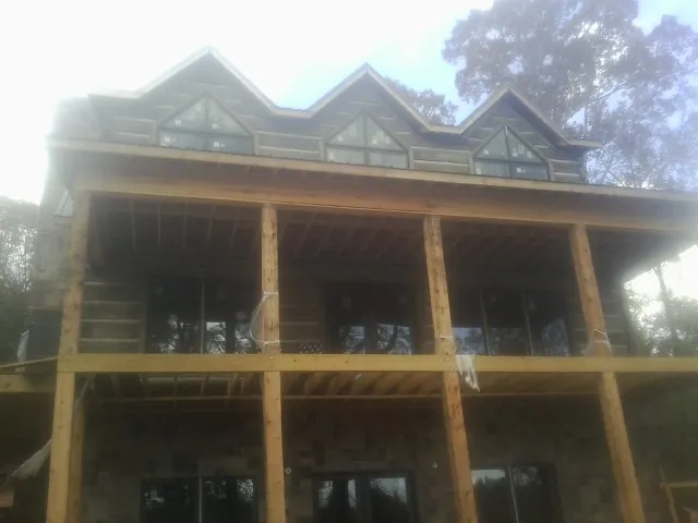 Dormers and porch framing on a large log home under construction — Roof Coating work by our crew in Creola
